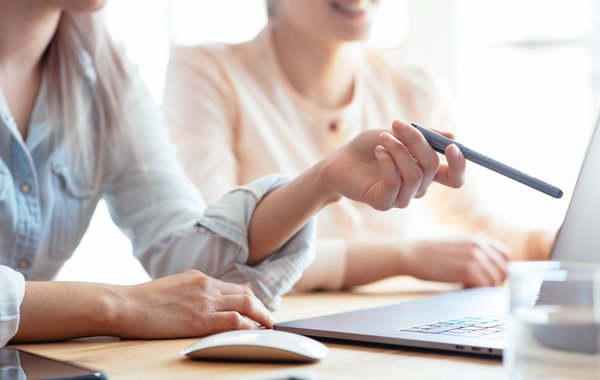 Mehrere Personen arbeiten mit Laptop, Unterlagen und Diagrammen an einem Tisch.